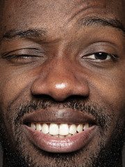 Close up portrait of young and emotional african-american man. Highly detail photoshot of male model with well-kept skin and bright facial expression. Concept of human emotions. Happy smiling, playful