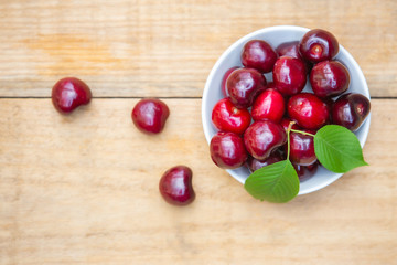 Top view fresh cherries in the white bowl on wood table