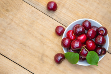 Top view fresh cherries in the white bowl on wood table