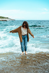 woman walking by rocky sea beach at sunny windy day. summer vacation
