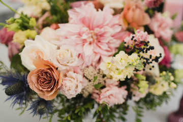 Coziness and style. Modern event design. Table setting at wedding reception. Floral compositions with beautiful flowers and greenery, candles, laying and plates on decorated table.