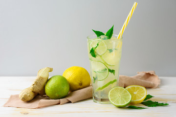 Cooling lemonade with lemon and lime, slices of ginger and mint leaves.