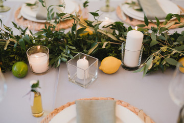 Coziness and style. Modern event design. Table setting at wedding reception. Floral compositions with beautiful flowers and greenery, candles, laying and plates on decorated table.