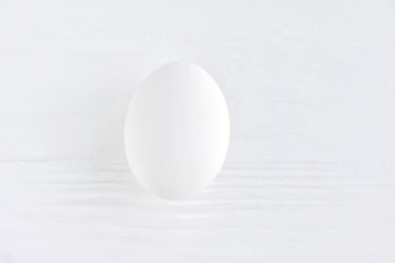 White chicken egg with selective focus on blurred textured gray background. Fresh organic fragility egg on neutral backdrop, soft focus. Ingredient for healthy diet breakfast. Easter symbol 