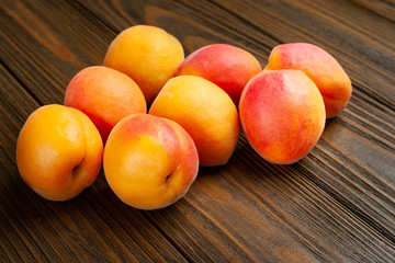 Ruddy apricots on a wooden background. Pile of fresh juicy apricots piled on a wooden table.