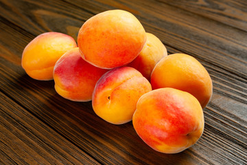 Ruddy apricots on a wooden background. Pile of fresh juicy apricots piled on a wooden table.