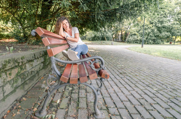 Young girl or woman sitting alone on the park bench feeling depressed and sad after she had argue and fight with her boyfriend or husband and she thinking about her life with sadness on her face
