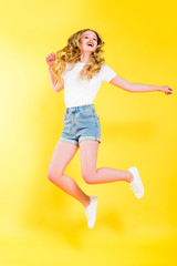 Fototapeta na wymiar beautiful happy blonde young woman jumping On yellow