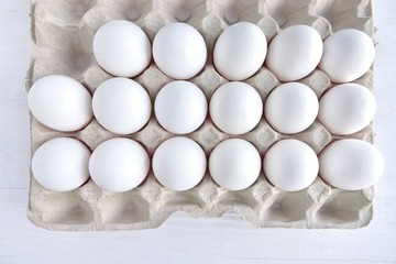 White organic hen eggs in carton recycling cardboard box on neutral background, selective focus. Dozen of raw farm chicken egg in carton box. Ingredient for delicious healthy breakfast. Easter symbol 