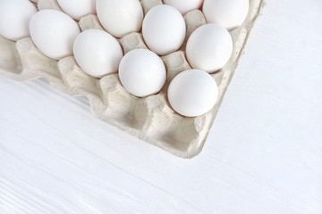 White organic hen eggs in carton recycling cardboard box on neutral background, selective focus. Dozen of raw farm chicken egg in carton box. Ingredient for delicious healthy breakfast. Easter symbol 