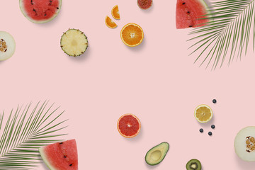 Summer exotic fruit top view flatlay with green palm leaves. Sliced watermelon, avocado, kiwi, orange, melon, grapefruit on minimal background