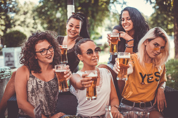 Happy group of best female friends drinking beer - Friendship concept with young female friends enjoying time and having genuine fun at outdoor nature ambient