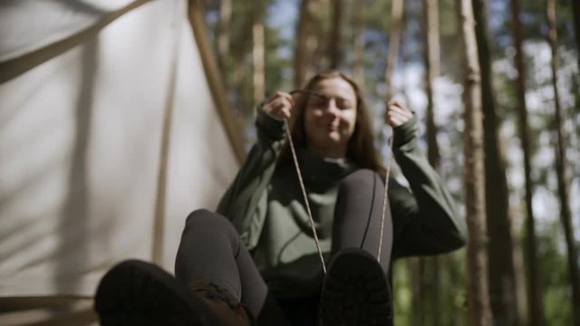 Girl tying shoelaces while sitting near tent. Slow motion