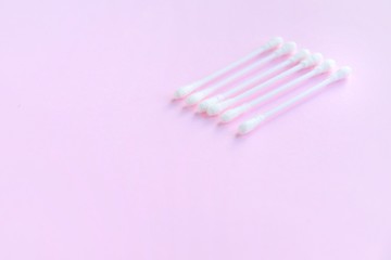 Row of white clean cotton swabs with selective focus on pink neutral background with empty space for text. Personal hygienic cotton buds for daily routine. Soft cotton ear sticks. Healthcare tools 