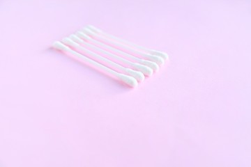 Row of white clean cotton swabs with selective focus on pink neutral background with empty space for text. Personal hygienic cotton buds for daily routine. Soft cotton ear sticks. Healthcare tools 