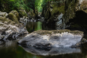 Naklejka na ściany i meble Big rock with water flowing down the gorge.
