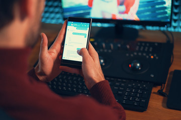 Young man working in the studio using a smartphone and computer.