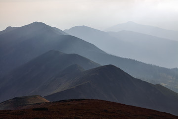 From the meadow opens a panoramic view of the mountains. Fantastic spring scenery. Touristic resort Carpathian national park, Ukraine Europe. The sun rays are breaking around.