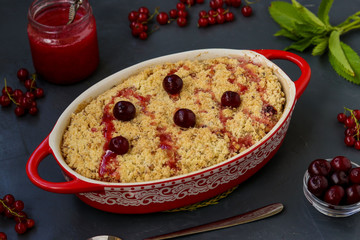 Homemade fresh cherry crumble pie with whole wheat flour in ceramic form on a dark background, ready to eat, horizontal photo