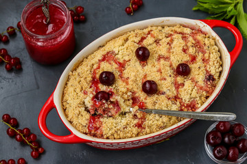 Homemade fresh cherry crumble pie with whole wheat flour in ceramic form on a dark background, ready to eat, horizontal photo