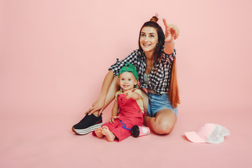 Stylish mother in a shirt and shorts. Little girl in a fashion clothes. Family have fun in a studio