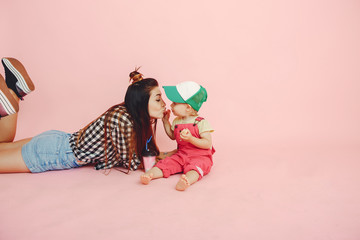 Stylish mother in a shirt and shorts. Little girl in a fashion clothes. Family have fun in a studio