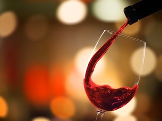 Red wine pouring in glass on  background