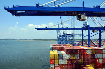 Gantry cranes are loading cargo on the container ship in port of Charleston, South Carolina.  