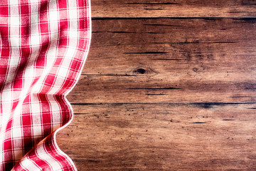 Checkered red napkin on an old wooden brown background, top view. Image with copy space. Kitchen table with a towel - top view with copy space. 