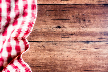 Checkered red napkin on an old wooden brown background, top view. Image with copy space. Kitchen table with a towel - top view with copy space. 