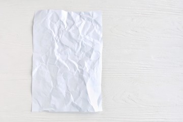 crumpled paper on white background for design banner or card, selective focus. Clear textured page with empty space for image or text on wooden white backdrop. Mockup concept 
