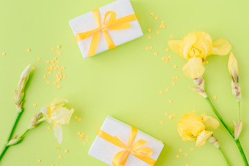 Flat lay composition with yellow irises and gift box on a green background