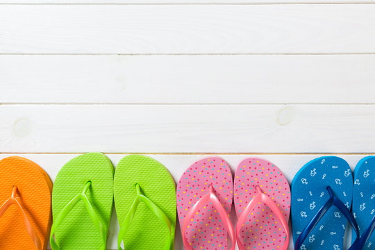 a lot of flip flop colored sandals, summer vacation on wooden background, copy space top view