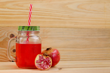 pomegranate juice in vintage Mason jar with red straw, red fruit.