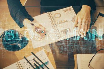 Cryptocurrency hologram over woman's hands writing background. Concept of blockchain. Double...