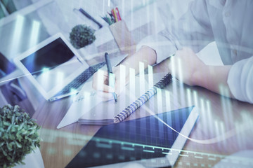 Financial graph displayed on woman's hand taking notes background. Concept of research. Double exposure