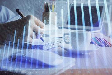 Financial chart drawn over hands taking notes background. Concept of research. Double exposure