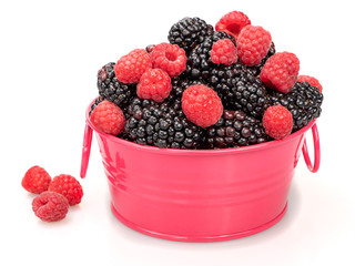 Ripe blackberries and raspberries in a raspberry basin and near it on a white background. Close-up. Still life.