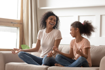 Healthy happy african mother teaching yoga happy kid daughter laughing