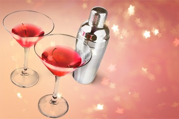 Glasses of red martini with cherries and silver shaker on white background
