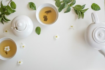 set with green tea, cups and kettle, mint leaves and chamomile flowers, with free space for text, long wide banner