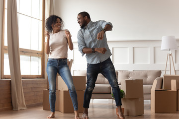 Happy african couple dancing laughing in living room with boxes