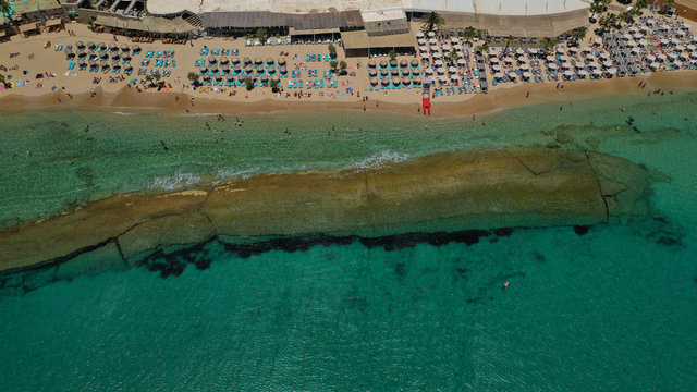 Aerial drone photo of famous organised with sun beds and umbrellas beach of  Paradise with emerald clear sandy sea shore, Mykonos island, Cyclades, Greece  