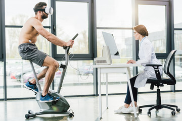 sportsman in vr headset and doctor sitting at computer desk during endurance test