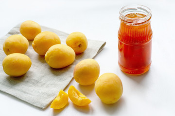 Apricot jam in a jar and fresh fruits on a white background
