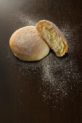 butter buns with powdered icing sugar on dark wood table