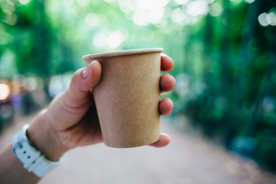 Woman's hand holding brown paper cup of coffee
