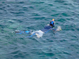 Hombre flotando y nadando, buceando y mirando el fondo del mar, puede respirar gracias a un tupo que sale al exterior y conecta con la boca, puede ver el fondo del mar gracias a unas gafas especiales