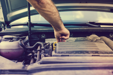 Checking liquids in the car. The man checks the level of fluids in the car with the car hood open. Concept of car breakdown, problems and attempts to locate a failure.