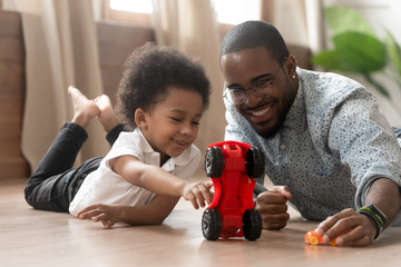 Cute little african kid son playing toy cars with dad